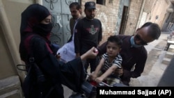 A health worker administers polio vaccine to a child in a neighborhood of Peshawar, Pakistan.