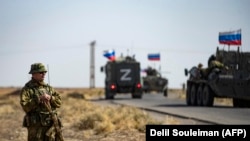 Солдаты из российского военного конвоя и американские военнослужащие наблюдают друг за другом в момент, когда маршруты их патрулирования пересеклись. Нефтяное месторождение недалеко от границы с Турцией. 8 октября 2022 года
