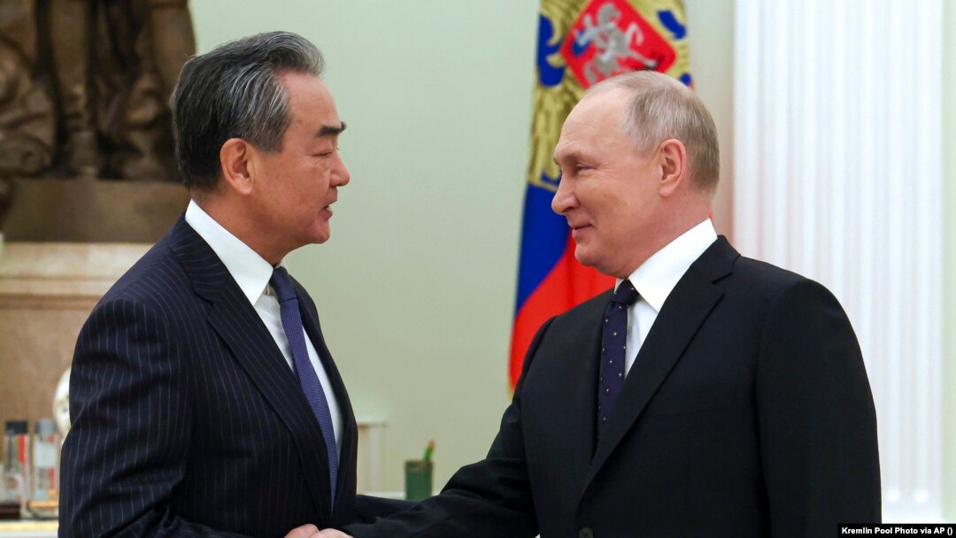 Russian President Vladimir Putin greets Chinese Communist Party's foreign policy chief Wang Yi during their meeting at the Kremlin on February 22.