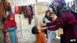 A health worker administers polio drops to a child during a door-to-door vaccination campaign in Karachi. 