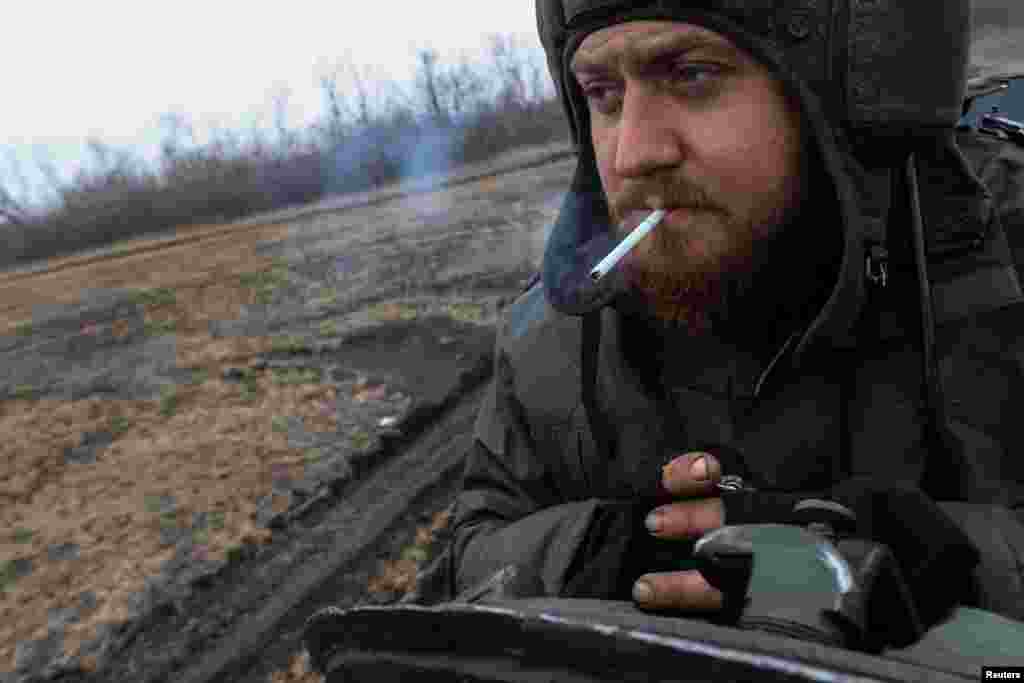 Ukrainian serviceman smokes as he rides on a tank near the frontline town of Bakhmut