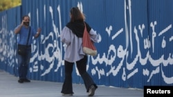 زنی جوان بدون حجاب اجباری در حال قدم زدن در خیابانی در تهران