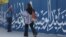زنی جوان بدون حجاب اجباری در حال قدم زدن در خیابانی در تهران