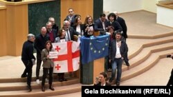 Oporbeni zastupnici u gruzijskom parlamentu slave povlačenje zakona o "stranim agentima" sa zastavama Gruzije i Europske unije, Tbilisi, 10. ožujka 2023.