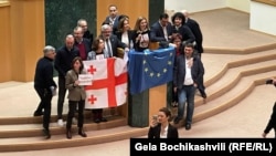 Opposition lawmakers in Georgia's parliament celebrate revoking the bill on "foreign agents" with the flags of Georgia and the EU on March 10.