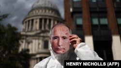 Një protestues me një maskë fytyre të presidentit të Rusisë, Vladimir Putin, gjatë një proteste në Londër: "Putini është vrasës", 20 gusht 2023.