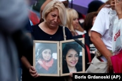 A woman shows pictures of her late relative at protests in Skopje on September 4.
