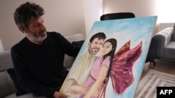 Mesut Hancer duke shikuar pikturën që ia dhuroi një artist, ku vajza e tij, Irmak, ësht pikturuar si engjëll përkrah të atit.