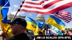 Люди держат флаги США и Украины возле Капитолия. Вашингтон, 20 апреля 2024 года 