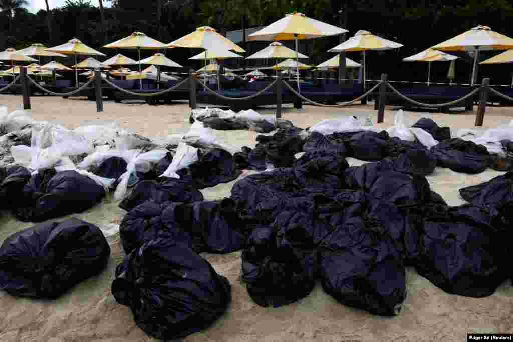 Qeset me rërë të kontaminuar nga nafta të bëra grumbull pranë një klubi plazhi në plazhin Tanjong në ishullin Sentosa, më 18 qershor 2024.