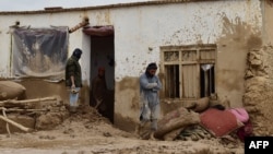 ساکنان یک خانه گلی در بغلان که در تلاش پاککاری خانه از سیلاب های اخیر اند 