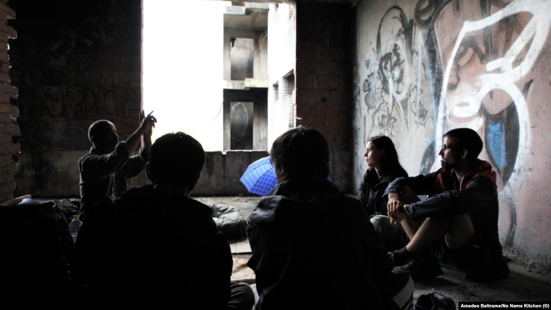 Chinese migrants talk in an abandoned building in Bihac, Bosnia, with volunteers from the humanitarian group No Name Kitchen. 