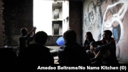 Chinese migrants talk in an abandoned building in Bihac, Bosnia, with volunteers from the humanitarian group No Name Kitchen. 