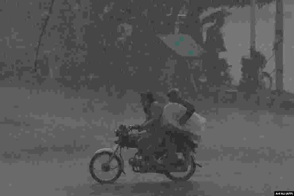 Motorcyclists ride along a street amid heavy rain in Lahore, Pakistan.