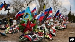 Flags wave over the recent graves of Russian soldiers killed in Ukraine at a cemetery in Russia’s Volgograd region.