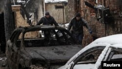 Ljudi iznose tijelo iz zapaljene kuće na mjestu napada ruskih dronova, usred ruskog napada na Ukrajinu, u Harkivu, Ukrajina, 10. februara 2024.