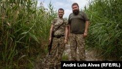Ukrainian soldiers Rostyslav (left) and Oleksandr patrol the riverbank in Prymorske.