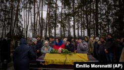 Rokonok gyászolják a 27 éves Jurij Kulikot koporsója mellett az ukrajnai Kalinyivkában 2023. február 21-én