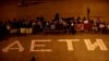 People with banners in front of chalk written word "Deti" in Prague [closer]