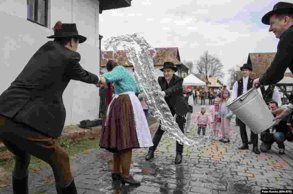 Dressed in folk costumes, young men pour water on a young woman in Holloko, a historic mountain village some 80 kilometers northeast of Budapest. According to an old Hungarian tradition, on Easter Monday young men pour water on young women, who in exchange present the men with hand-decorated colored eggs.