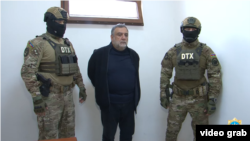 Former Karabakh premier Ruben Vardanyan flanked by Azerbaijani security officers appears before an interrogator after his arrest and transfer to Baku in late September 2023.