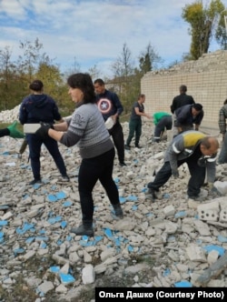 Teachers sort debris from the damaged school.