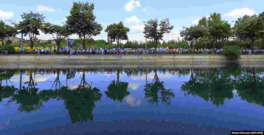 Romanian teachers are reflected into the waters of the Dabovita River as they march for better pay and conditions in Bucharest.&nbsp;