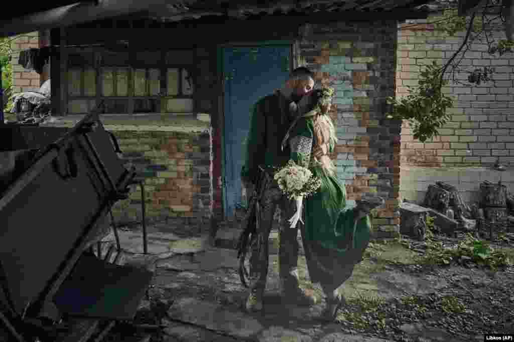 Volunteer military medics, code names Nikita and Polka, wearing traditional clothing, share a kiss during their wedding ceremony at their position on the front line in the Donetsk region, Ukraine.