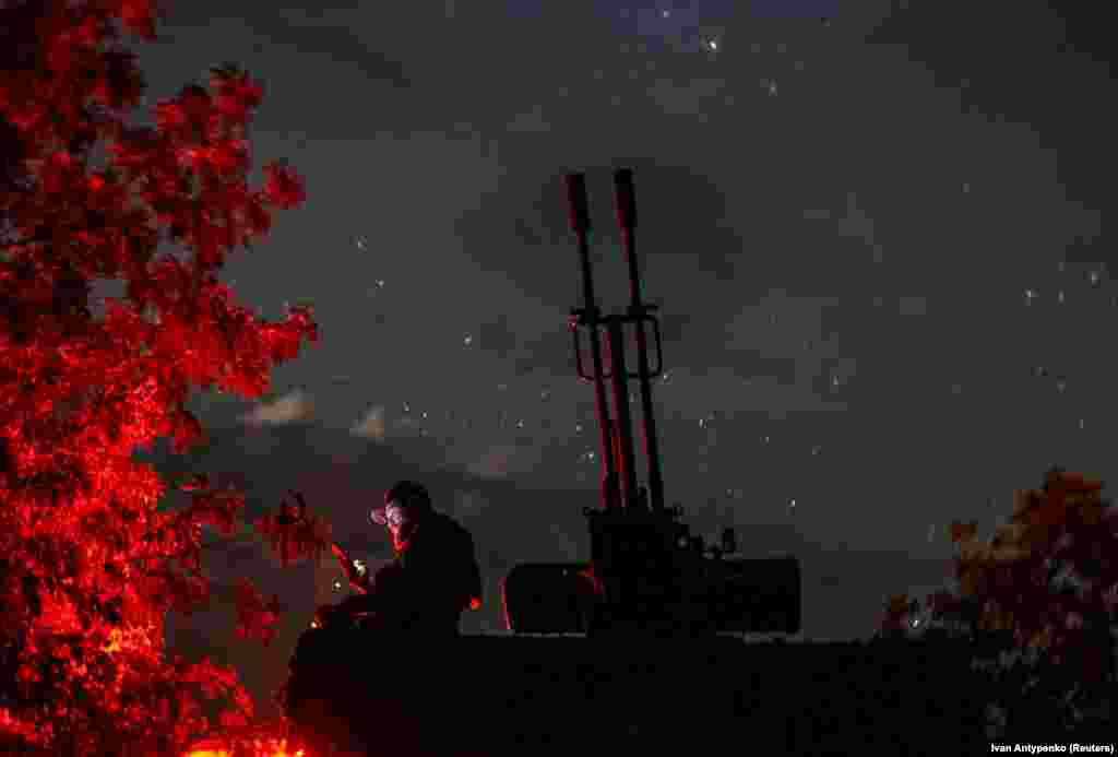 A Ukrainian soldier from an anti-drone mobile air defense unit uses his mobile device near a ZU-23-2 anti-aircraft cannon as he waits for Russian kamikaze drones amid Russia&#39;s attack on Ukraine, in the Kherson region.