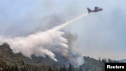 Пожежний літак скидає воду під час лісової пожежі біля села Ваті, на острові Родос, Греція, 25 липня 2023 року