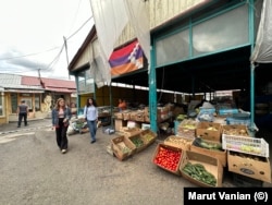 Localnicii din Stepanakert trec pe lângă legumele de vânzare pe 18 iulie. Produsele cultivate local sunt vândute la prețuri de câteva ori mai mari decât cele obișnuite spun localnicii, făcându-le de neatins pentru mulți oameni.