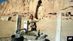 Авганистанец пумпа вода во близина на археолошкиот локалитет на статуата на Буда во Бамијан, централен Авганистан, 18 декември 1997 