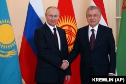 Russian President Vladimir Putin (left) and Uzbek President Shavkat Mirziyoev shake hands ahead of an informal meeting of the heads of ex-Soviet republics which are members of the Commonwealth of Independent States in St. Petersburg on December 26, 2022.
