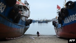 Muškarac nosi kantu vode da očisti trup ribarskog čamca u selu Tailu, na kineskoj obali nasuprot tajvanskih ostrva Matsu, u kineskoj jugoistočnoj provinciji Fujian 25. maja 2024.