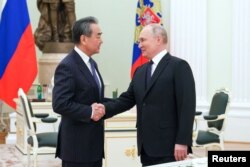 Președintele Rusiei, Vladimir Putin, dă mâna cu directorul Biroului Comisiei Centrale a Afacerilor Externe din China, Wang Yi, în timpul unei întâlniri la Moscova, Rusia, 22 februarie 2023.
