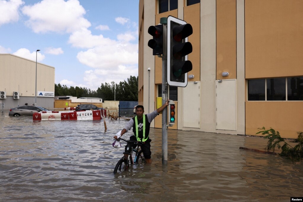 Një djalë me biçikletë kalon përmes ujërave nga përmbytjet. 