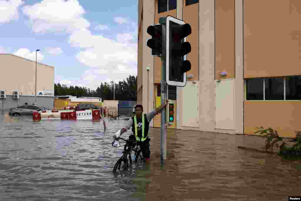 Një djalë me biçikletë kalon përmes ujërave nga përmbytjet.&nbsp;