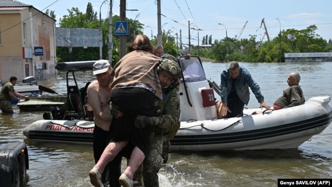 Українські військовослужбовці допомагають вивантажити літню жінку з човна під час евакуації із затопленої території в Херсоні, 8 червня 2023 року