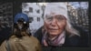 Një grua shikon një nga fotografitë e ekspozitës "Ukraina: Një krim lufte", që u hap në Prishtinë më 29 prill 2024. 