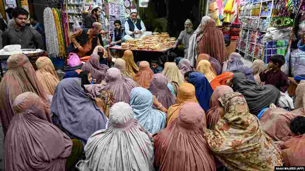 Femei îmbrăcate în burqa așteaptă pâine gratuită la un punct de distribuire a ajutoarelor în Peshawar, Pakistan.