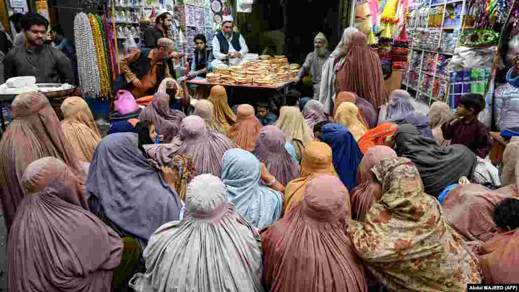 Femei îmbrăcate în burqa așteaptă pâine gratuită la un punct de distribuire a ajutoarelor în Peshawar, Pakistan.