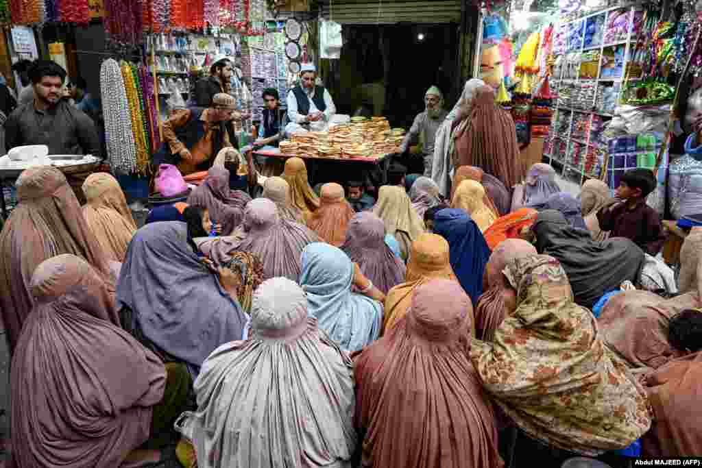 Burqa-clad women wait for free bread at an aid distribution point in Peshawar, Pakistan.&nbsp;