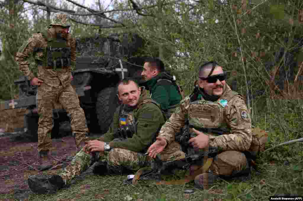 Ukrainian artillerymen rest near their vehicles.