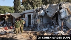 دو سرباز اسرائیلی بر ویرانه‌های خانه‌ای در کیبوتص کفر آزا در جنوب اسرائیل و نزدیکی غزه