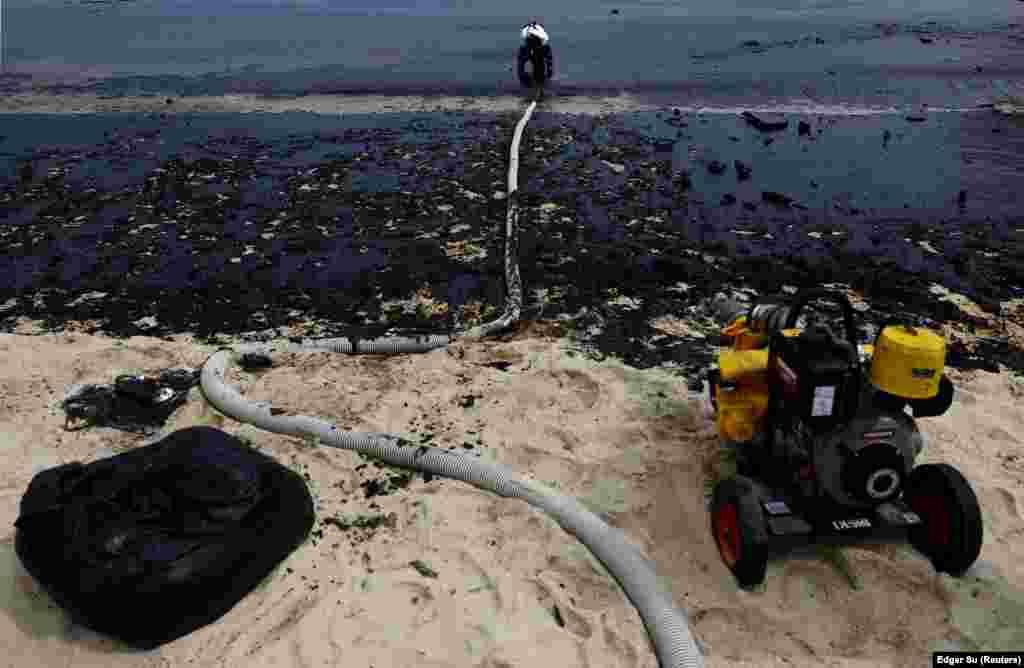Një punëtor duke operuar me një sistem vakumi gjatë pastrimi të masave të naftës në plazhin Tanjong në Sentosa.