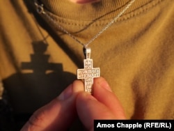 A Lipovan from Sarichioi holds the cross worn by Old Believers in Romania that features the phrase "God will rise again and all his enemies will perish."