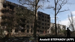 Un bărbat trece pe lângă case distruse de focul de artilerie și raidurile aeriene în satul Oceretîne din regiunea Donețk, la mijlocul lunii aprilie.