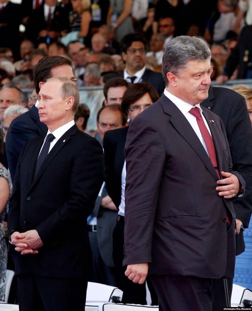 Gjatë shënimit të 70-vjetorit më 2014, presidenti i zgjedhur i Ukrainës, Petro Poroshenko (djathtas), kalon pranë presidentit rus, Vladimir Putin, duke e shpërfillur praninë e tij mes tensioneve mbi aneksimin e paligjshëm të Krimesë nga Rusia, që kishte ndodhur tre muaj më parë. Në një përpjekje për të zgjidhur krizën e shkaktuar nga separatistët e mbështetur nga Rusia në Ukrainën lindore dhe nga aneksimi i Krimesë nga Moska, presidenti i atëhershëm francez Francois Hollande kishte ftuar homologët e tij rusë dhe ukrainas, në një përpjekje për t&#39;i ulur tensionet për konfliktin.