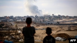Dečaci posmatraju dim koji se diže tokom izraelskih napada istočno od Rafaha u južnom pojasu Gaze 13. maja 2024. 