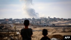 Dy djem duke e shikuar tymin që ngrihet lart nga ndërtesat në Rafah, Gazë, gjatë sulmeve izraelite kundër Hamasit, 31 maj 2024.